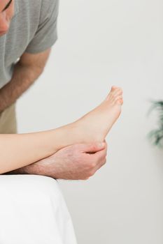 Podiatrist examining the foot of his patient in a room