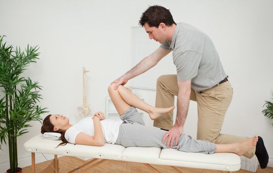 Woman being examining her leg by a chiropractor in a medical room