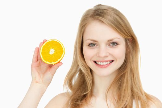 Joyful woman presenting an orange against white background