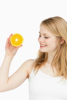 Joyful woman holding an orange against white background