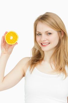 Smiling woman presenting an orange against white background