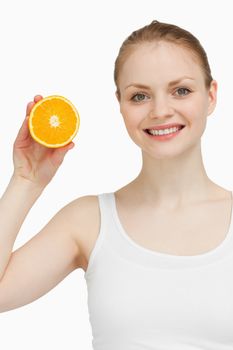 Smiling woman holding an orange against white background