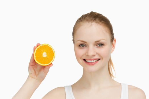 Cheerful woman presenting an orange against white background