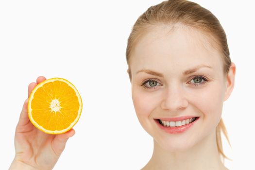 Close up of a cheerful woman presenting an orange against white background