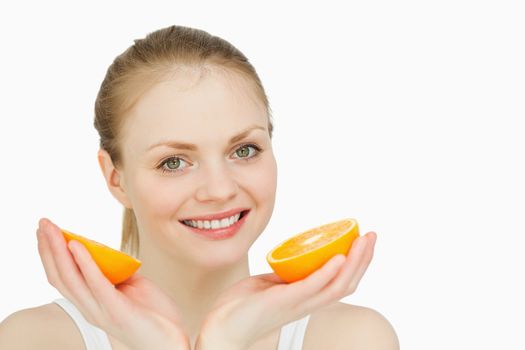 Smiling woman holding oranges against white background