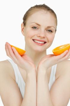 Close up of a smiling woman holding oranges against white background