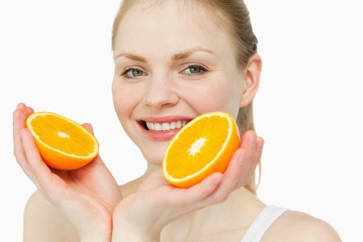 Close up of a cheerful woman holding oranges against white background