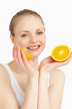 Cheerful woman holding oranges while smiling against white background