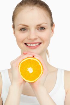 Smiling woman holding an orange in her hands against white background