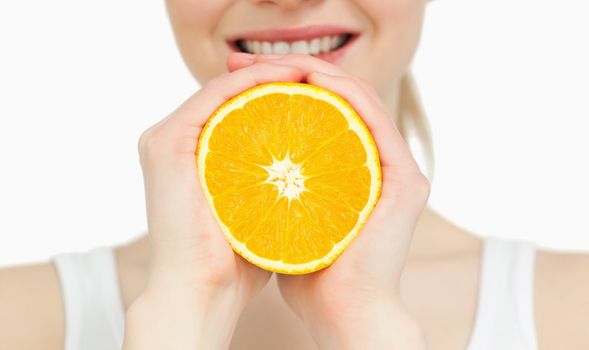 Close up of a woman holding an orange against white background
