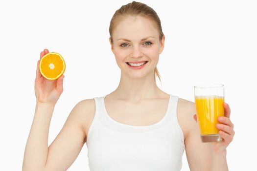 Woman holding a glass while presenting an orange against white background