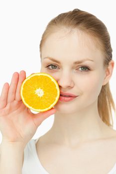 Woman placing an orange on her lips against white backgroun