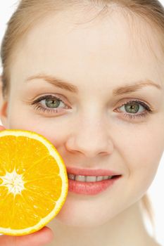 Close up of a woman placing an orange on her lips