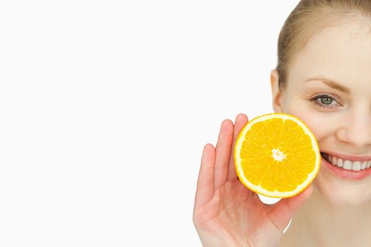 Close up of a woman holding an orange in her hand against white background