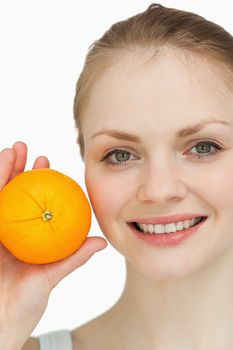 Fair-haired woman presenting an orange against white background