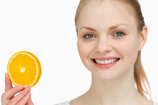 Smiling woman presenting an orange slice against white background