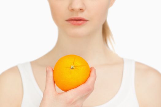 Woman holding an orange against white background