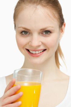 Smiling woman holding a glass of orange juice against white background