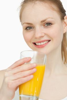 Cheerful woman holding a glass of orange juice against white background