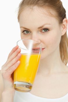 Woman drinking a glass of orange juice against white background