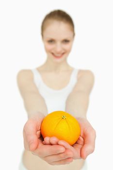 Close up of a woman presenting a tangerine against white background