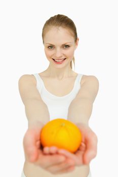 Smiling woman presenting a tangerine against white background