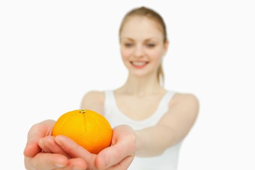 Cheerful woman presenting a tangerine against white background