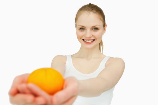 Joyful woman presenting a tangerine against white background