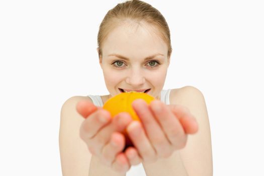 Blonde-haired woman holding a tangerine against white background