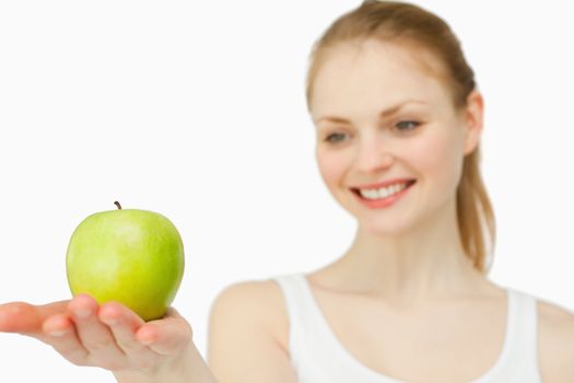 Woman smiling while presenting an apple against white background