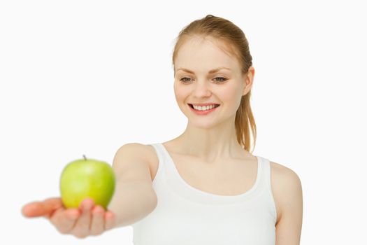 Cheerful woman presenting an apple against white background