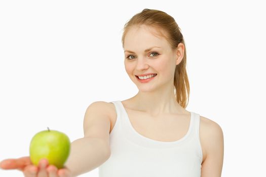 Woman smiling while holding an apple against white background