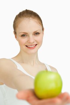 Young woman presenting an apple against white background