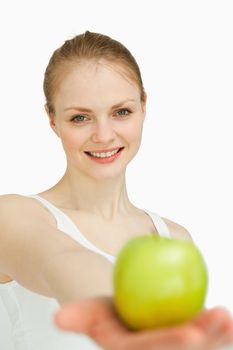 Young woman presenting an apple against white background