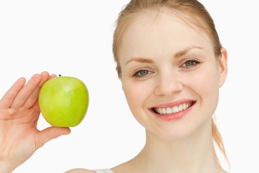 Blonde-haired girl smiling while holding an apple against white background