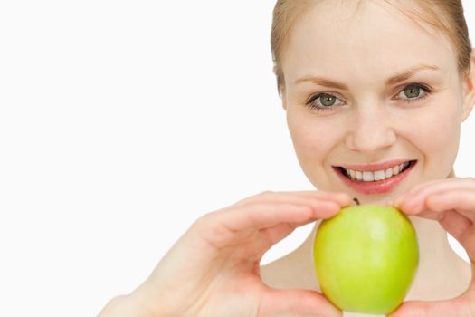 Joyful blond-haired woman presenting an apple against white background