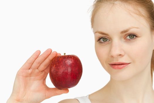 Young blonde-haired woman presenting an apple against white background