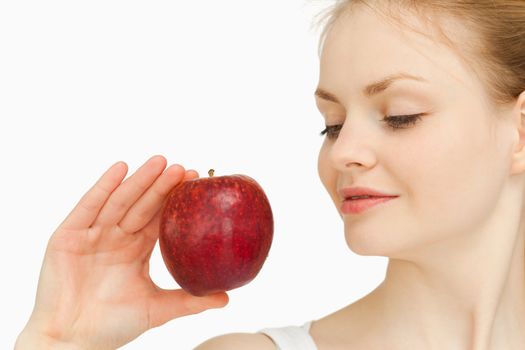 Woman holding an apple while looking at it against white background