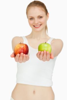 Cheerful woman presenting two apples against white background