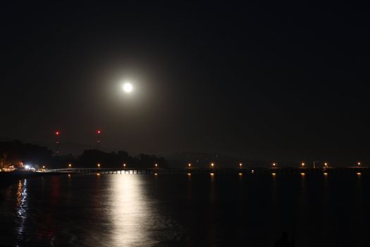 Full Moon over the Goleta Pier with reflection on the ocean.