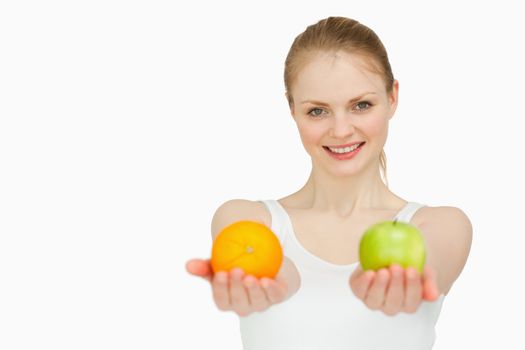 Young woman smiling while presenting fruits against white background