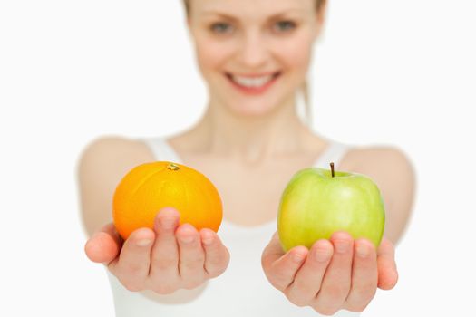 Young woman presenting fruits while smiling against white background