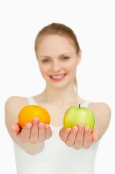 Close up of a young woman presenting fruits against white background