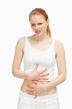 Suffering woman placing her hands on her stomach against white background