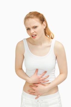 Woman placing her hands on her painful stomach against white background