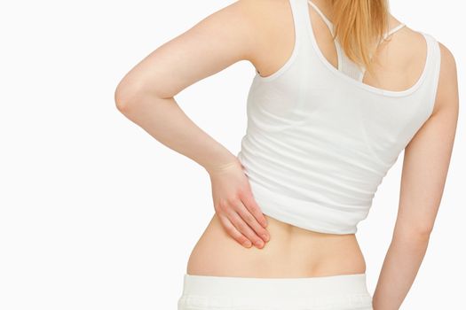 Woman standing while massaging her back against white background