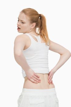 Young woman massaging her back against white background