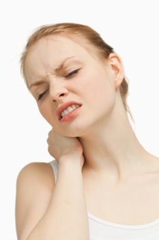 Young woman massaging her painful nape against white background