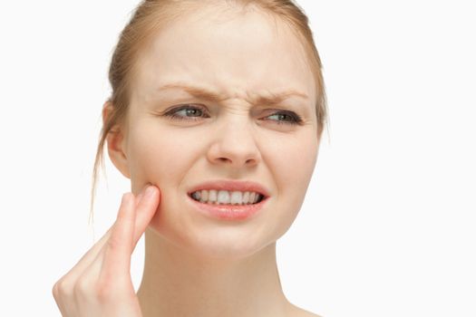 Woman massaging her cheek against white background