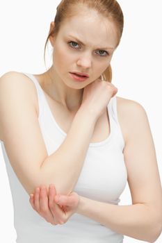 Blonde woman touching her elbow against white background